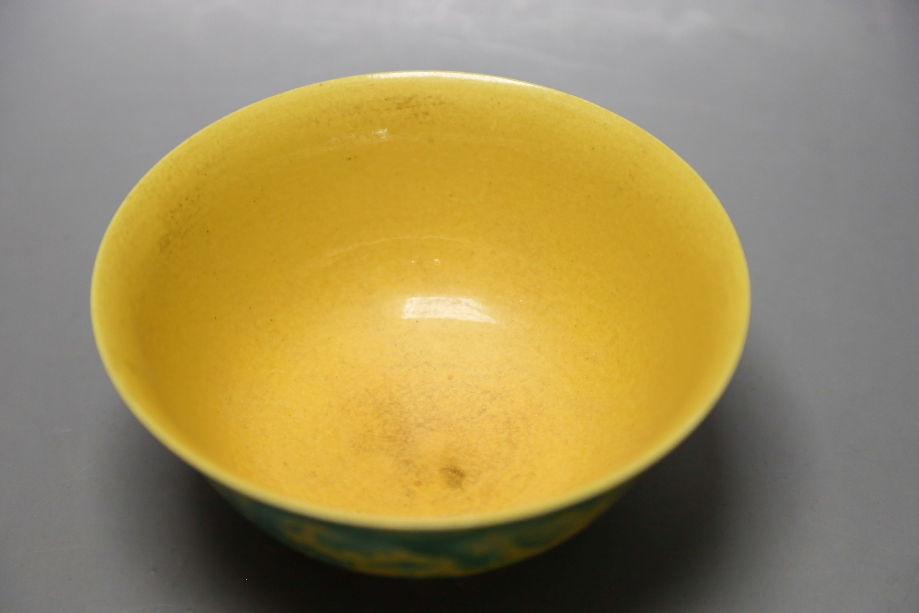 A Chinese yellow ground sgraffito’dragon’ bowl, Kangxi mark but later 15cm diameter